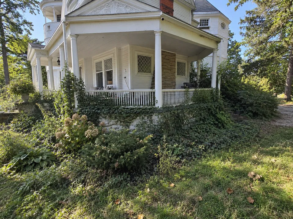 A rendering of the porch corner as it was: ivy up the stone foundation and the railing, and weeds through the beds.
